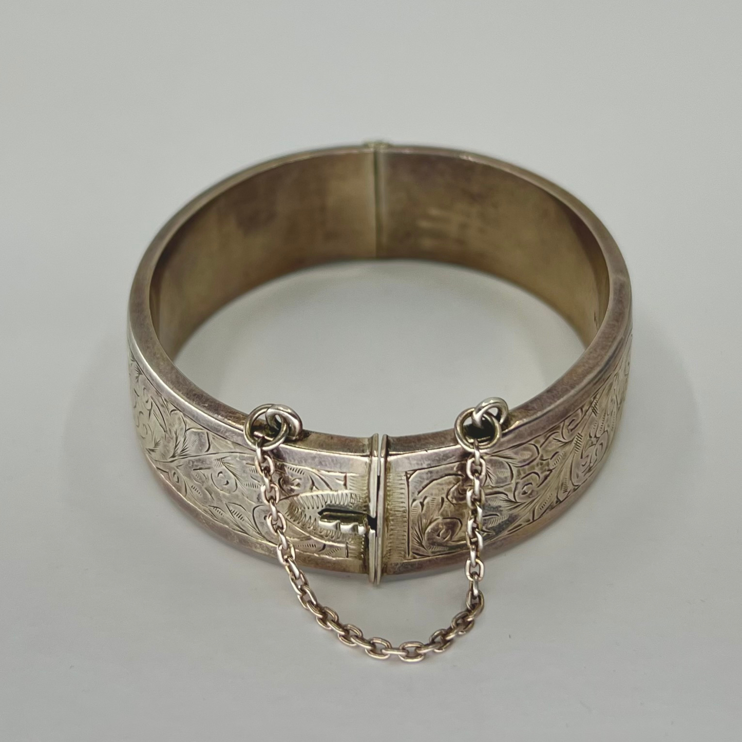 Vintage silver hand-etched hinged bangle with button clip and safety chain. Hudsons Estate Jewellery
